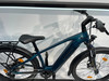 Ein blaugrünes Elektrofahrrad mit Gepäckträger und Frontlicht.