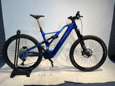 Ein blaues Fully-Elektrofahrrad mit schwarzen Rädern und goldener Sattelstütze. Ein blaues Fully-Elektrofahrrad mit schwarzen Rädern und goldener Sattelstütze.