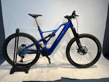 Ein blaues Fully-Elektrofahrrad mit schwarzen Rädern und goldener Sattelstütze.