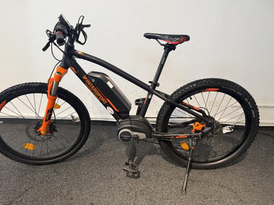 Schwarzes E-Bike mit orangefarbenen Details und Intersport-Aufschrift auf dem Rahmen. Schwarzes E-Bike mit orangefarbenen Details und Intersport-Aufschrift auf dem Rahmen.