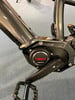 Nahaufnahme eines E-Bikes mit Yamaha-Logo und Kurbel auf grauem Teppich.
