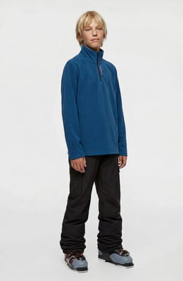 Junge in blauem Fleece-Pullover und schwarzer Skihose mit Skischuhen. Junge in blauem Fleece-Pullover und schwarzer Skihose mit Skischuhen.