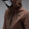 Ein Mann in einer braunen Oakley-Jacke und Skibrille blickt nach unten.