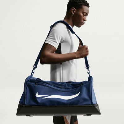 Ein Mann mit einer dunkelblauen Nike-Sporttasche über der Schulter.