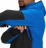 Ein Mann in einer blauen Jacke mit schwarzen Ärmeln schließt den Reißverschluss.