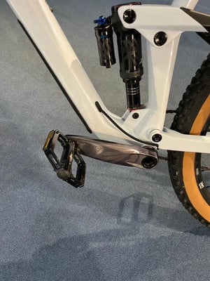 Detail eines Mountainbikes mit Dämpfer und Pedal auf blauem Untergrund. Detail eines Mountainbikes mit Dämpfer und Pedal auf blauem Untergrund.