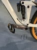Detail eines Mountainbikes mit Dämpfer und Pedal auf blauem Untergrund.