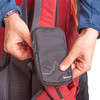 Eine Hand schließt eine kleine schwarze Tasche am Rucksack.