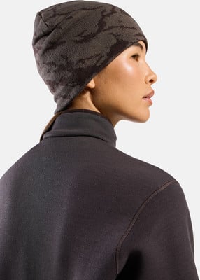 Eine Frau mit einer dunklen gemusterten Mütze und einem dunklen Rollkragenpullover.