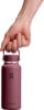Eine Hand hält eine weinrote Hydro Flask Flasche am Griff.