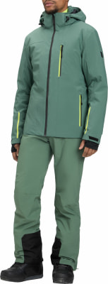 Ein Mann in einer grünen Skijacke und Hose mit gelben Details.