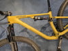 Ein gelbes Mountainbike mit Federung und schwarzen Rädern auf blauem Hintergrund.