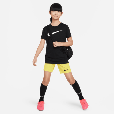 Mädchen im schwarzen Nike-Shirt und gelben Shorts mit Umhängetasche. Mädchen im schwarzen Nike-Shirt und gelben Shorts mit Umhängetasche.