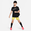 Mädchen im schwarzen Nike-Shirt und gelben Shorts mit Umhängetasche.