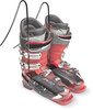 Rote Skischuhe mit schwarzen Riemen und Schnallen auf weißem Grund.