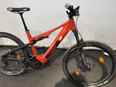 Orange vollgefederte Mountainbike mit schwarzen Rädern und Intersport-Logo. Orange vollgefederte Mountainbike mit schwarzen Rädern und Intersport-Logo.