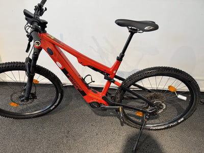 Ein rotes E-Bike mit schwarzem Sattel und schwarzen Rädern auf dunklem Untergrund. Ein rotes E-Bike mit schwarzem Sattel und schwarzen Rädern auf dunklem Untergrund.