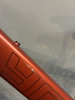 Orangefarbener Fahrradrahmen mit schwarzem Logo und kleinem Kratzer.
