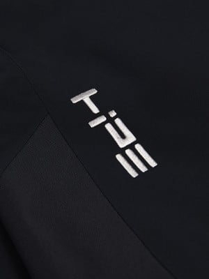Detail eines schwarzen Stoffes mit weißem Logo im oberen Bereich. Detail eines schwarzen Stoffes mit weißem Logo im oberen Bereich.
