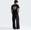 Mann in schwarzem T-Shirt mit Aufdruck und schwarzer Hose mit Tasche.