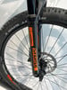 Vorderradgabel eines Fahrrads von SR Suntour mit orangefarbenem Logo und Bremsscheibe.