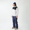 Ein Mann in einer blauen Mütze, einem weiß-schwarzen Fleece-Pullover und blauen Skihosen.