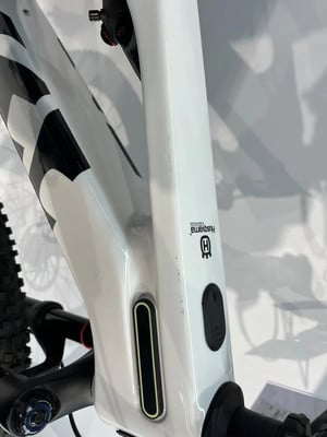 Detail eines weißen E-Bike-Rahmens mit Husqvarna-Logo und Ladeanschluss. Detail eines weißen E-Bike-Rahmens mit Husqvarna-Logo und Ladeanschluss.