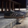 Fekete Adidas sneakerek leopárdmintás csíkokkal és gumitalppal lépcsőkön.