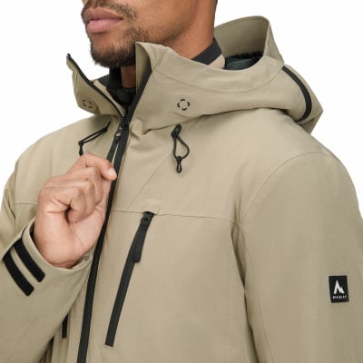 Ein Mann in einer beigen Kapuzenjacke mit schwarzen Reißverschlussdetails. Ein Mann in einer beigen Kapuzenjacke mit schwarzen Reißverschlussdetails.