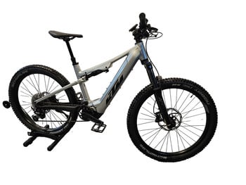 Ein silbernes KTM Mountain E-Bike mit Federung und schwarzen Rädern.