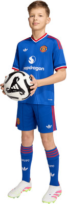 Ein Junge hält einen Fußball im Manchester-United-Trikot und Shorts. Ein Junge hält einen Fußball im Manchester-United-Trikot und Shorts.