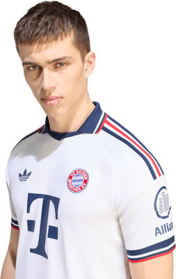 Junger Mann in einem weißen Fußballtrikot mit dem FC Bayern München Logo. Junger Mann in einem weißen Fußballtrikot mit dem FC Bayern München Logo.