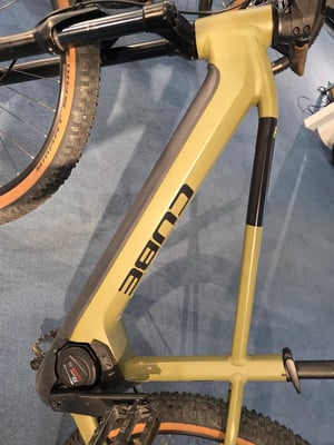 Ein goldenes Cube E-Mountainbike mit Rahmenlogo und Bosch-Motor.