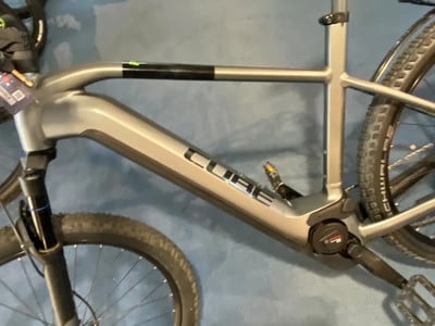 Grauer E-Bike-Rahmen mit CUBE-Logo und schwarzen Pedalen. Grauer E-Bike-Rahmen mit CUBE-Logo und schwarzen Pedalen.