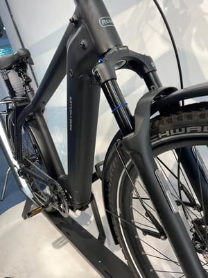 Ein schwarzes E-Bike von Riese & Müller mit Federgabel und Akku.