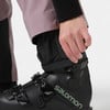 Eine Hand passt den Kordelzug am Hosenbein eines Skischuhs an.
