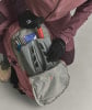 Eine Person holt Ausrüstung aus einem Rucksack, darunter eine Pumpe und Skistöcke.