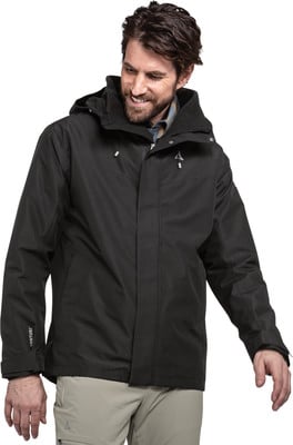 Ein Mann in schwarzer Jacke und beiger Hose lächelt vor weißem Hintergrund. Ein Mann in schwarzer Jacke und beiger Hose lächelt vor weißem Hintergrund.