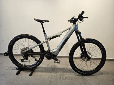 Ein silbernes KTM E-Mountainbike auf einem Ständer mit Federung und Scheibenbremsen.
