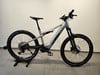 Ein silbernes KTM E-Mountainbike auf einem Ständer mit Federung und Scheibenbremsen.