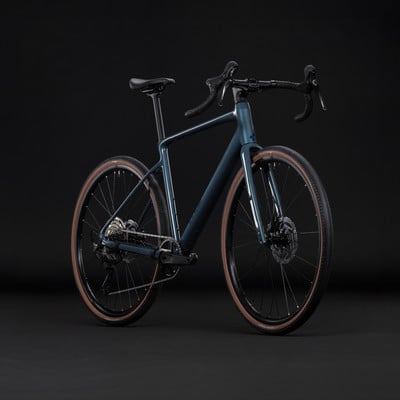 Dunkelblaues Gravelbike mit braunen Reifen vor schwarzem Hintergrund. Dunkelblaues Gravelbike mit braunen Reifen vor schwarzem Hintergrund.