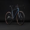 Dunkelblaues Gravelbike mit braunen Reifen vor schwarzem Hintergrund.