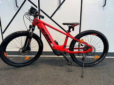 Ein rotes KTM E-Bike mit schwarzen Rädern und Federung auf einem Ständer.