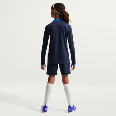 Ein Mädchen in einem dunkelblauen Fußballtrikot mit weißem Streifen und blauen Shorts. Ein Mädchen in einem dunkelblauen Fußballtrikot mit weißem Streifen und blauen Shorts.