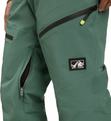 Detail einer Herrenhose mit schwarzen Reißverschlüssen und einem Logo im Oberschenkelbereich. Detail einer Herrenhose mit schwarzen Reißverschlüssen und einem Logo im Oberschenkelbereich.