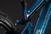 Detail des hinteren Teils eines blauen E-Mountainbikes mit Dämpfer und Logo.
