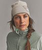 Eine Frau in einer Strickmütze und grüner Jacke mit Zopf.