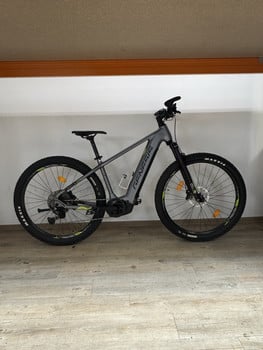 Graues E-Mountainbike mit schwarzen Rädern und gelben Details.