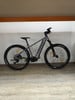 Graues E-Mountainbike mit schwarzen Rädern und gelben Details.