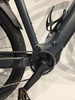 Detail eines Elektrofahrrads mit Pedal und Kette auf grauem Hintergrund.